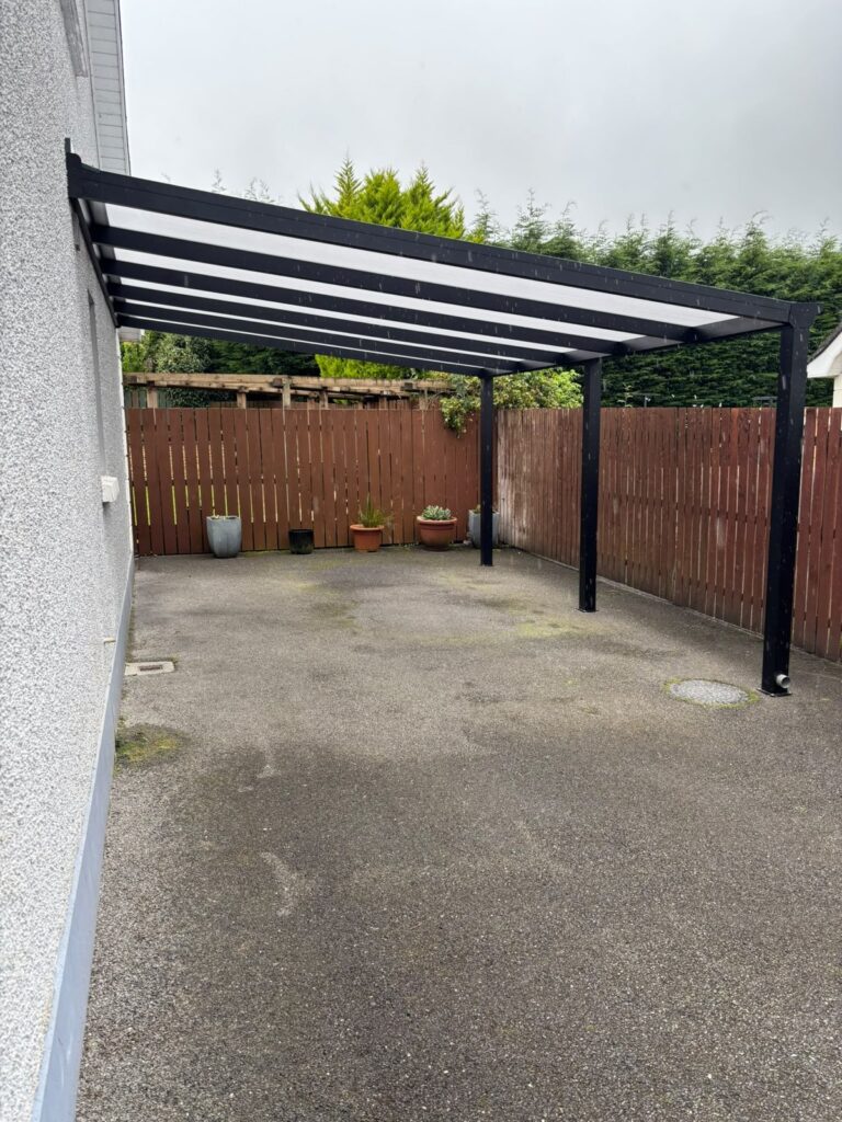 Freestanding carport against a fence