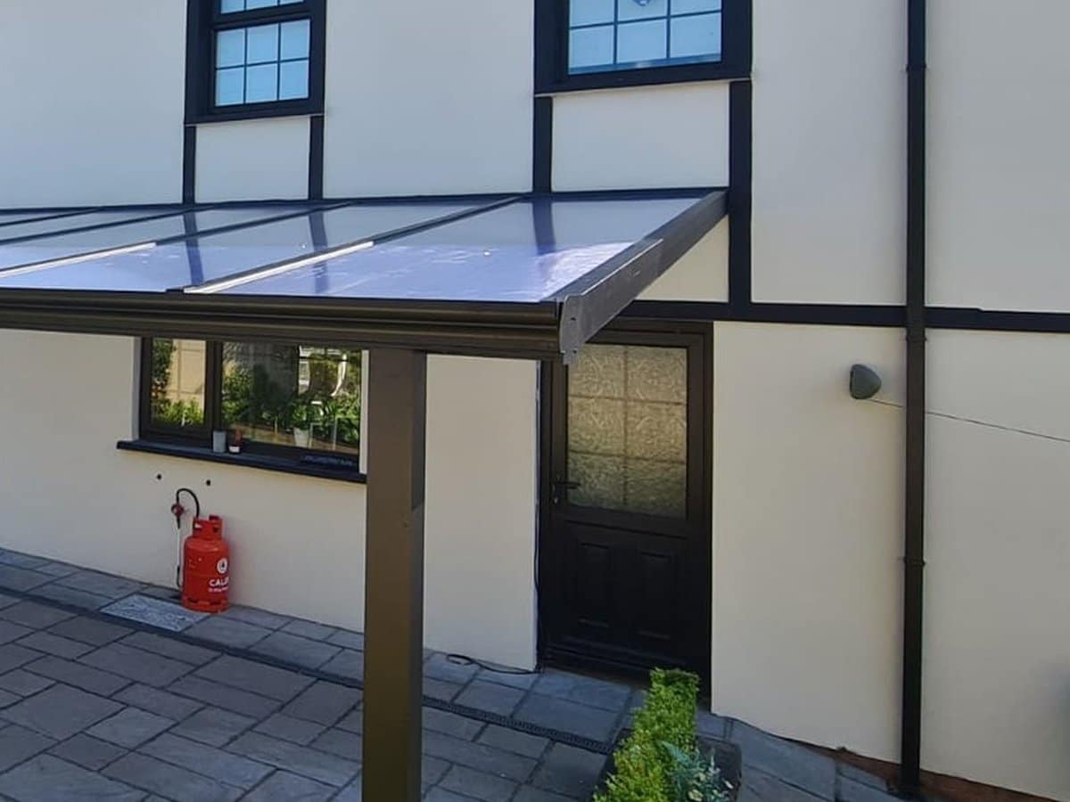 Slate grey veranda with a clear roof along the back of a house in Derry