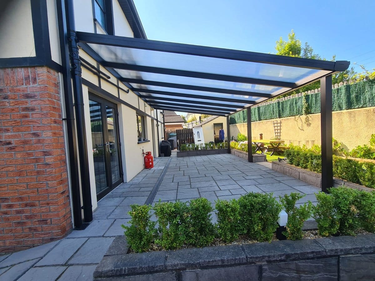 Slate grey aluminium veranda with a clear roof running the length of a patio in Derry