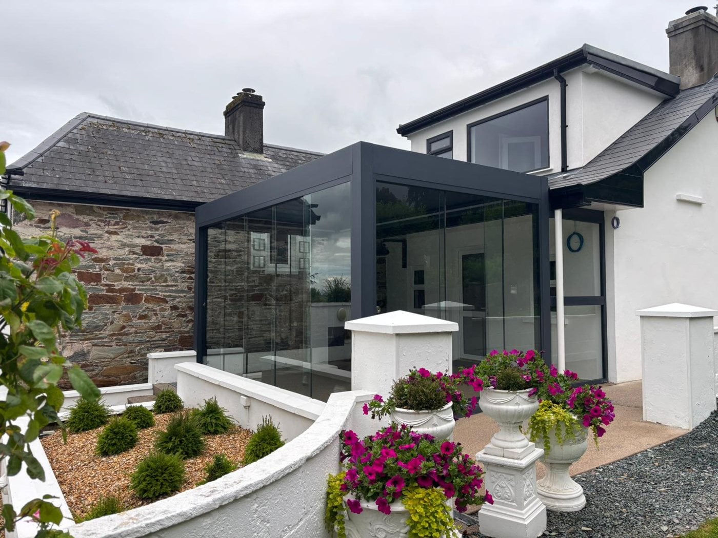 Glass room with a retractable aluminium roof and frameless glass sliding doors